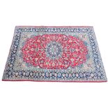 * A large Iranian wool rug, with a traditional blue medallion radiating trailing foliage upon a