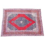 * An Iranian wool rug, the red ground with a central serrated lozenge medallion, enclosed by