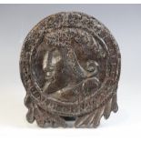 An early 16th century carved oak Romayne type roundel, carved with a male in profile hung with