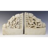 A pair of carved stone brackets, each depicting a female figure in elaborate robes upon a shell