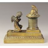 A brass desk inkwell, 19th century, designed as a cherub kneeling before a memorial plinth,