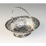 A George III silver swing handled sweetmeat basket, of oval form with pierced and repoussé