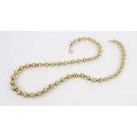 A gold coloured beaded necklace, designed as a single row of graduated beads with engraved floral