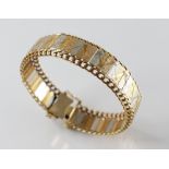 A gold coloured bracelet, comprising alternating panels in yellow, rose and white gold hues, flanked