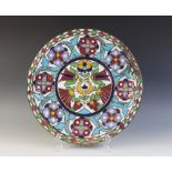 An Islamic influence enamelled copper charger, of circular form, decorated in floral motifs with
