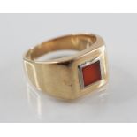 A gold coloured carnelian set signet ring, the central square carnelian panel measuring 6mm x 6mm,