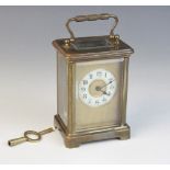 An early 20th century brass cased carriage timepiece, the 5cm ivory coloured ceramic dial applied