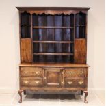 A George III oak dresser, the enclosed plate rack with a moulded cornice over a shaped apron and