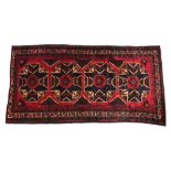 An Afghan Belouch wool rug, in red, blue and green colourways, the central deep red field with
