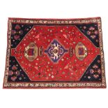 A Persian Qashqai style wool rug, in red and blue colourways, the central red field with three