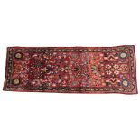 An Iranian floral pattern wool runner, the central red field overlaid with multi coloured floral