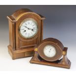 An Edwardian oak cased mantel clock, the arched case enclosing a 13cm white enamelled dial applied