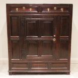 An 18th century oak panelled hall/livery cupboard, formed as a central cupboard door below two