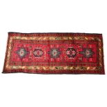 An Iranian Heriz type wool runner, the five central geometric medallions on a vibrant red field,