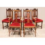 A set of four early 20th century oak dining chairs, each with a carved crest rail above a wavy