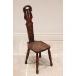 A late Victorian carved oak spinning chair, the carved and pierced high back rest centred with