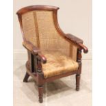 A Regency mahogany bergère library chair, the curved back extending to the down swept padded arms
