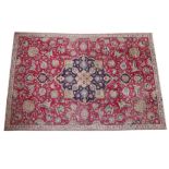 A Persian hand knotted wool carpet, the traditional foliate deign on a red ground with a central