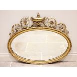 An Adams style gilt wood and gesso oval wall mirror, 19th century, the frame surmounted with an