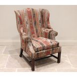 A George III style wing back armchair, late 20th century, with shaped wing backs extending to padded