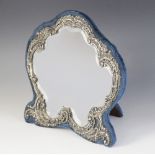 An Edwardian silver mounted mirror, Henry Matthews, Birmingham 1902, the shaped mirror with embossed