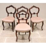 A set of four Victorian walnut balloon back dining chairs, each with a 'C' scroll and foliate carved