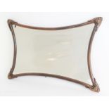 An Art Nouveau style wall mirror, the copper effect shaped tubular frame with with cast acanthus