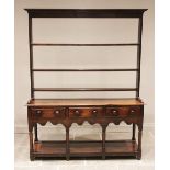 An early 19th century oak Welsh dresser, the open plate rack with a moulded cornice over three