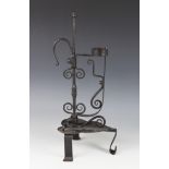 An Arts & Crafts wrought iron rush lamp, supported on a leaf shaped base upon three legs, the