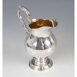 A Victorian silver milk jug, London 1857 (maker's mark worn), of baluster form on circular foot with