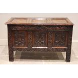 A 17th century and later carved oak coffer, the hinged three panelled cover opening to a candle box,