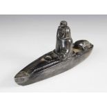 A Inuit stone carving, modelled as a fisherman in a canoe/Umiak, 24.5cm long