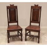 A pair of Charles II style oak hall chairs, late 20th century, each with a panelled back above a