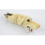 A Victorian carved ivory dog whistle, modelled as a hound with glass eyes and gold coloured ring