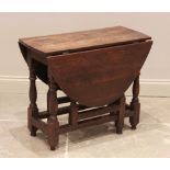 An 18th century oak drop leaf table, the oval top raised upon turned baluster and block supports,