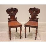 A pair of Regency mahogany hall chairs, the shaped backs centred with a recessed painted armorial