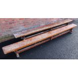 A pair of mid century stained wooden school gym benches, each raised on three trestle type supports,
