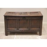 An early 18th century oak coffer, the three panel hinged top, above a nulled frieze and three