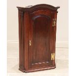 A George III oak hanging corner cupboard, the arched cornice above a single fielded panelled door
