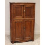 A late George III oak freestanding corner cupboard, formed as two pairs of panelled cupboard