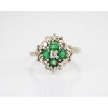 An emerald and diamond quatrefoil cluster ring, comprising a central round brilliant cut diamond