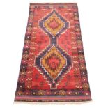 An Afghan Baluchi rug, in red and blue colourways, the two linked lozenge shaped medallions,