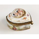 A Capodimonte porcelain heart-shaped box and cover, decorated in relief Putti to the hinged cover