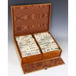 A Mahjong set, early 20th century, comprising four trays of thirty six bamboo-backed bone tiles