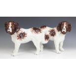 A pair of Staffordshire spaniels, each modelled standing with separate legs, one facing left, the