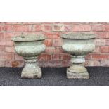 A pair of reconstituted stone garden urns, of lobed bowl form raised upon an integrated plinth base,
