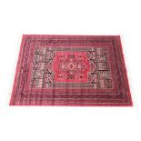 A full pile Afghan style carpet, the all over geometric design upon a red ground, enclosed by