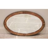 An Arts & Crafts planished copper framed oval wall mirror, early 20th century, the frame embossed