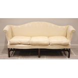 A George III mahogany serpentine sofa, later re-covered in damask fabric, the arched shaped back
