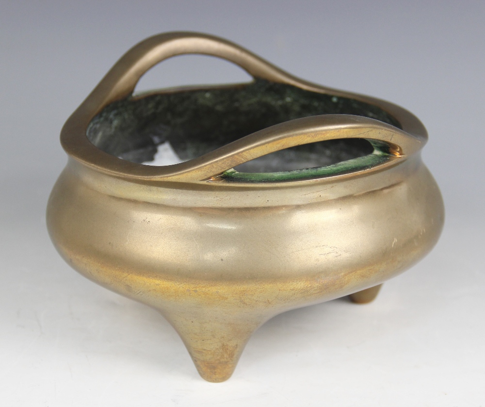 A Chinese polished bronze censer, Xuande mark, of typical plain circular form raised on three legs